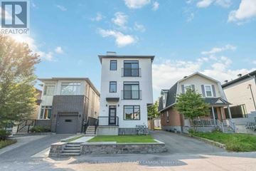 Ottawa triplex for rent - A modern two-story house with a white exterior and a black front door is surrounded by a well-maintained lawn and other residential homes.