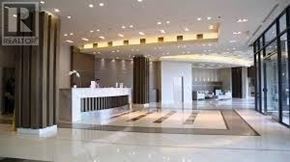 Toronto (Waterfront Communities) condo for rent - The image shows a well-lit, spacious lobby with a reception desk and a glass door leading to another room.