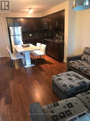 Toronto (Waterfront Communities) condo for rent - A modern kitchen with dark wood cabinets and a white dining table.