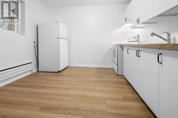 London East (East H) multi-family for rent - A kitchen with white cabinets and a white fridge.