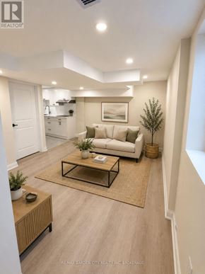 St. Catharines (Carlton/Bunting) apartment for rent - A well-lit, modern living room with a white sofa, a coffee table, and a rug.