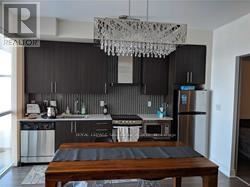 Toronto (Waterfront Communities) condo for rent - A modern kitchen with a wooden table in the middle.