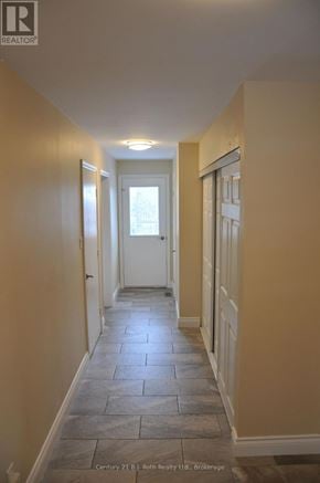 Orillia duplex for rent - A hallway with stone tiles flooring and white doors.