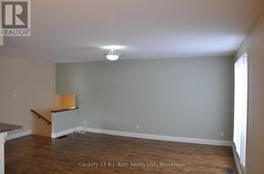 Orillia duplex for rent - A room with a wooden floor and a white ceiling with a light fixture.