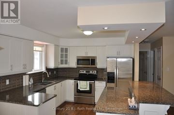 Orillia duplex for rent - A kitchen with white cabinets and a black countertop.