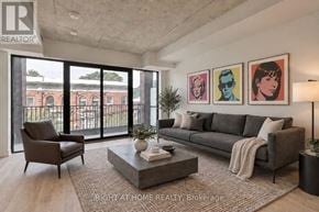 Toronto (South Riverdale) condo for rent - A living room with a grey couch, a coffee table, and a large window with a view of a building.