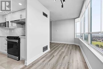 Mississauga (Fairview) condo for rent - A modern kitchen with white cabinets and a large window overlooking a cityscape.