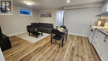 Mississauga (Lakeview) apartment for rent - A living room with a black couch and a wooden floor.