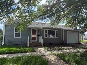 Kearney apartment for rent - A house with a red door is surrounded by greenery.