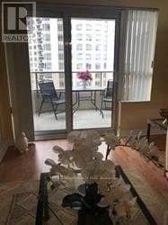Mississauga (Hurontario) condo for rent - A glass table with a flower arrangement on it in a room with a view of a balcony.