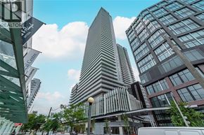 Toronto condo for rent - A tall building with a pointed top is surrounded by other buildings.