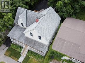 Huntsville fourplex for rent - A house with a grey roof and a red chimney is surrounded by greenery.