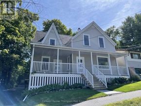 Huntsville fourplex for rent - A two-story house with a white porch and a grey roof.