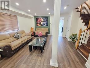 Mississauga (Meadowvale Village) apartment for rent - A living room with a brown couch, a glass coffee table, and a staircase.