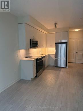 Toronto (Mimico) condo for rent - A kitchen with white cabinets and a refrigerator.