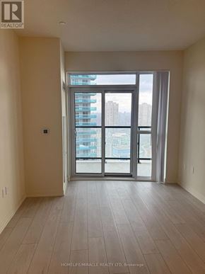Toronto (Mimico) condo for rent - A spacious room with a view of a cityscape through a large window.