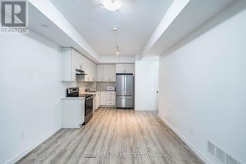 Brampton (Fletcher's Creek South) townhouse for rent - A spacious kitchen with white cabinets and a wooden floor.