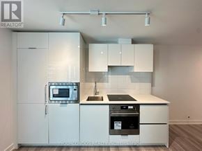 Toronto (Kensington-Chinatown) condo for rent - A modern kitchen with white cabinets and appliances.