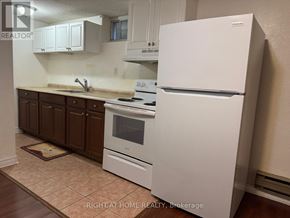 Richmond Hill (Crosby) apartment for rent - A white refrigerator stands in a kitchen with brown cabinets and a tiled floor.