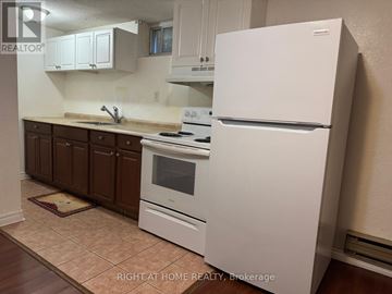 Richmond Hill (Crosby) apartment for rent - A white refrigerator stands in a kitchen with brown cabinets and a tiled floor.
