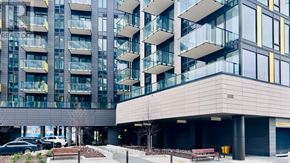 Oakville (Jm Joshua Meadows) condo for rent - A modern building with a glass facade and a covered walkway.