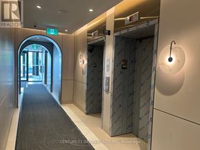 Oakville (Jm Joshua Meadows) condo for rent - A hallway with elevators and a green exit sign.
