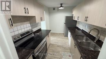 Toronto (Black Creek) condo for rent - A kitchen with a stove top oven and a sink.