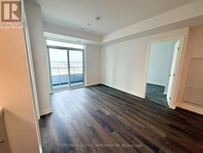Vaughan (Vaughan Corporate Centre) condo for rent - A room with wooden floors and a large window overlooking a balcony.