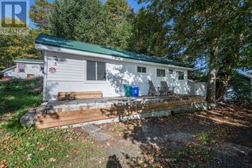 Huntsville (Chaffey) apartment for rent - A small white house with a green roof is surrounded by trees.