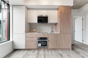Toronto (Moss Park) condo for rent - A modern kitchen with wooden cabinets and a stainless steel oven.