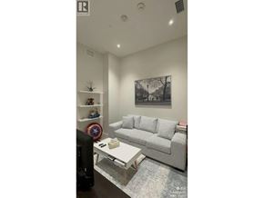 Vancouver apartment for rent - A living room with a grey couch, a coffee table, and a wall with a picture and a shelf with toys.