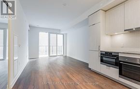Toronto (Moss Park) condo for rent - A spacious kitchen with wooden floors and white appliances.