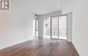 Toronto (Moss Park) condo for rent - A spacious room with wooden floors and sliding glass doors.