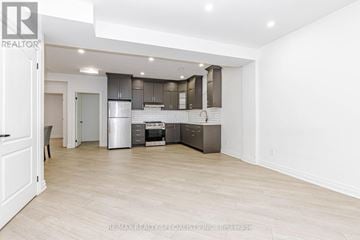 Brampton (Bram East) apartment for rent - A spacious kitchen with white cabinets and a wooden floor.