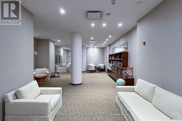 Toronto (Mimico) condo for rent - A spacious living room with white furniture and a carpeted floor.
