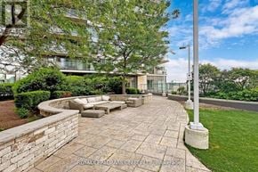 Toronto (Mimico) condo for rent - A sunny day in a courtyard with a stone wall and a grassy area.