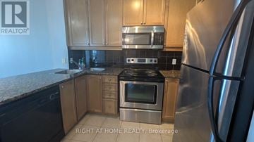 Mississauga (City Centre) condo for rent - A kitchen with a stainless steel refrigerator and black countertops.