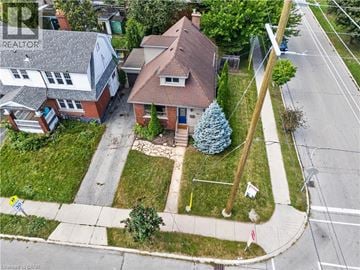 Hamilton apartment for rent - A house with a red roof and a blue door is surrounded by a green lawn and a sidewalk.