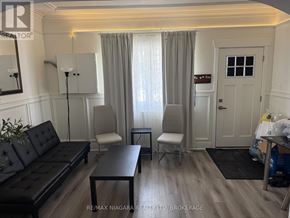 Port Colborne (East Village) multi-family for rent - A living room with a black leather couch and a wooden coffee table.