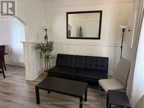 Port Colborne (East Village) multi-family for rent - A black sofa with a mirror above it in a room.