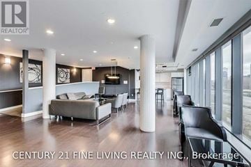 Toronto (Niagara) condo for rent - A spacious living room with a grey sofa and black chairs.