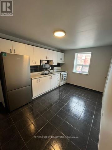 Toronto (Trinity-Bellwoods) apartment for rent - A kitchen with black tile flooring and white cabinets.