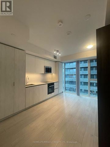 Toronto (Waterfront Communities) condo for rent - A modern kitchen with wooden cabinets and a large window.