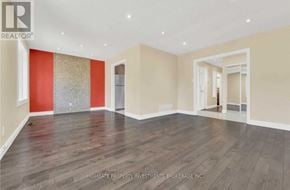 Brampton (Madoc) apartment for rent - A spacious room with wooden flooring and a red accent wall.