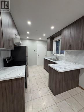 Waterloo apartment for rent - A kitchen with brown cabinets and a black fridge.