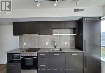 Toronto (Waterfront Communities) condo for rent - A modern kitchen with black cabinets and stainless steel appliances.