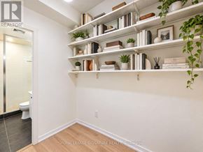 Toronto (Niagara) condo for rent - A white bathroom with a toilet and a shelf with plants and books.
