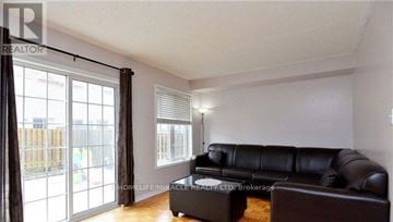 Brampton (Brampton East) apartment for rent - A living room with a black leather couch and a coffee table.