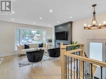 Brampton (Bram East) apartment for rent - A living room with a black leather chair and a wooden railing.
