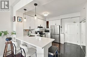 Toronto (Long Branch) condo for rent - A white kitchen with a large island and a refrigerator.